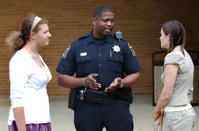 A police officer speak to two young women